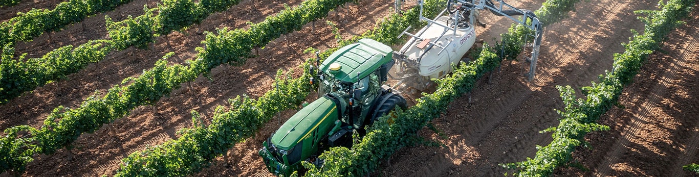 Three John Deere specialty tractors lined up in an orchard