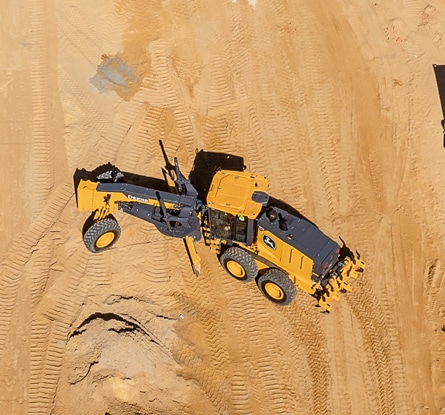 Aerial view of a John Deere motor grader working on a dirt construction site