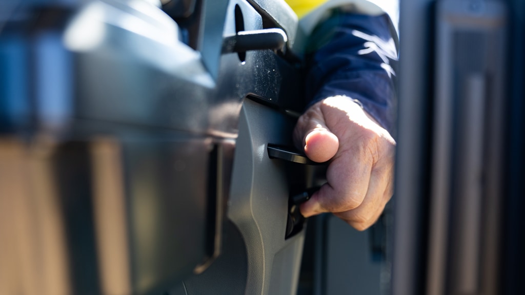 Close-up of a hand adjusting a seat control inside a John Deere motor grader cab.