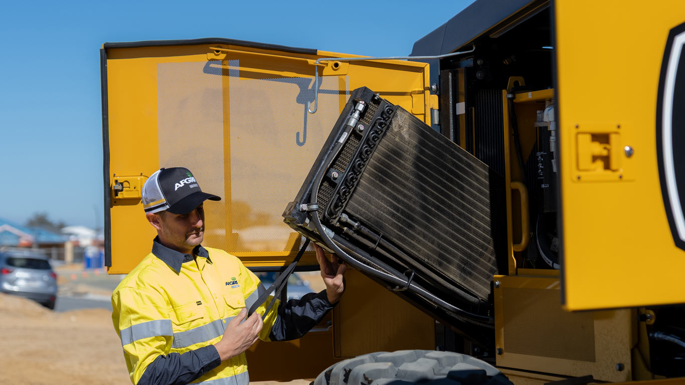 Close-up of maintenance filters and fluid system components inside a John Deere motor grader.