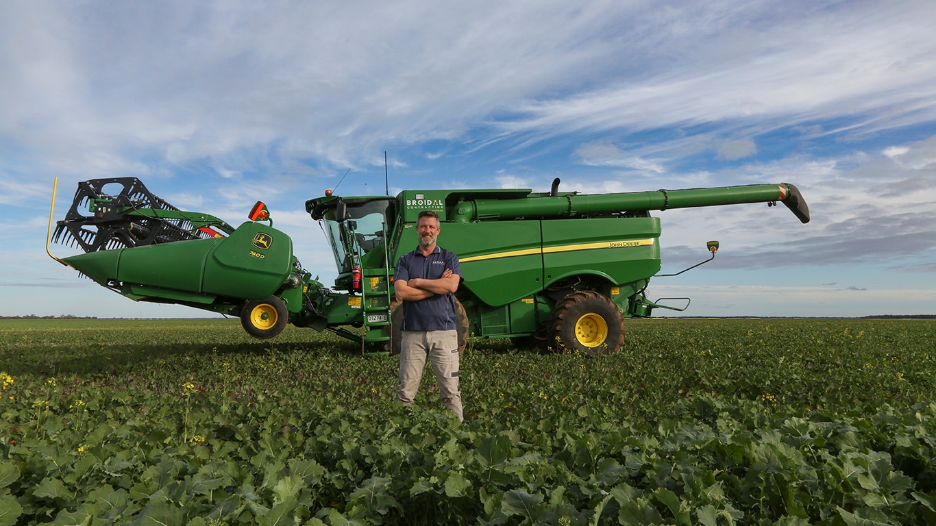 Gavin smiling in a field in front of his 740D combine