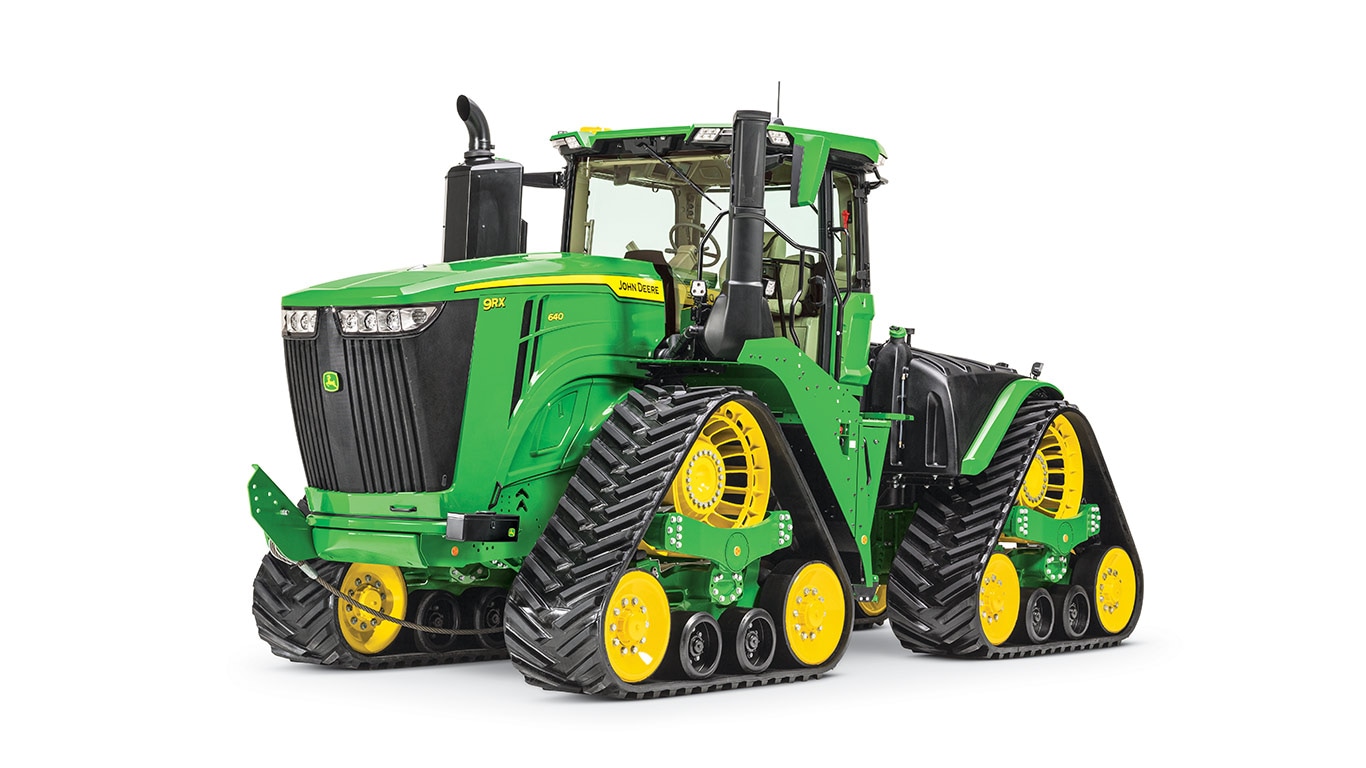 Green John Deere 957R tractor with yellow-black tracks, viewed from the front-left side.