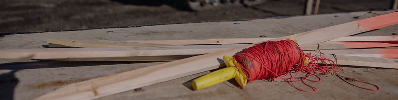 Close up of grading stakes with 333G SmartGrade CTL driving in the background