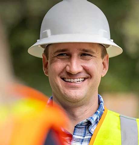 Smiling construction worker with hard hat and orange safety vest