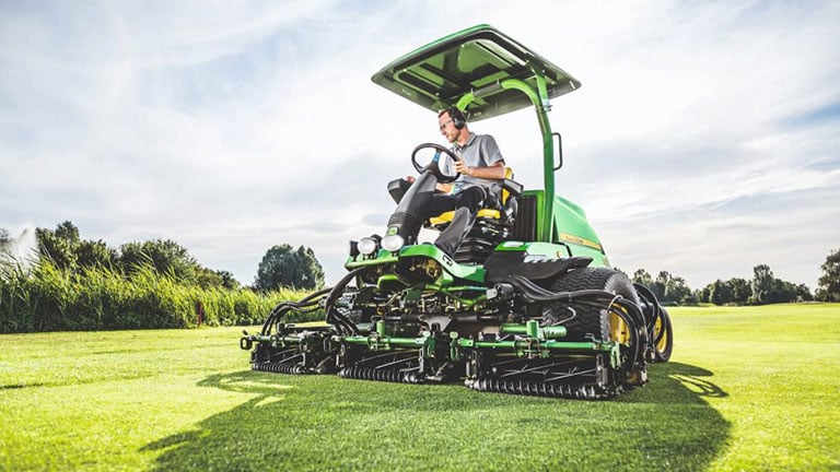 person on fairway mower on golf course