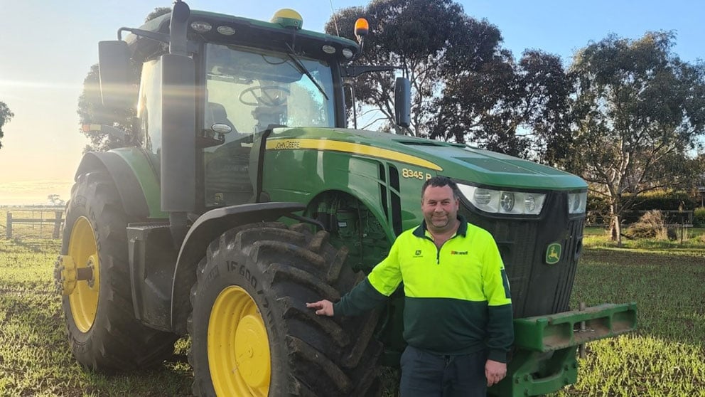 William Lawless in front of a John Deere tractor in a field