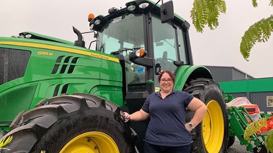 Caitlin Williams next to John Deere equipment