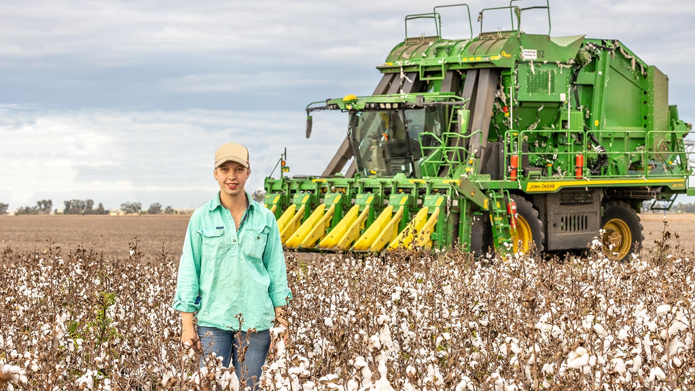 Laura Keeley, female Cotton grower in a field with a John Deere Cotton Harvester