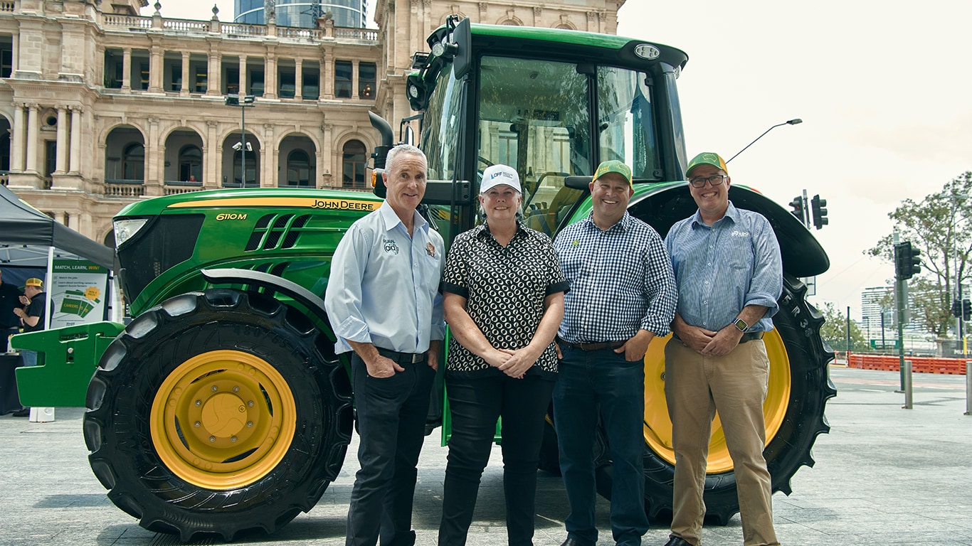 A group of people standing in front of a 6110 M tractor.