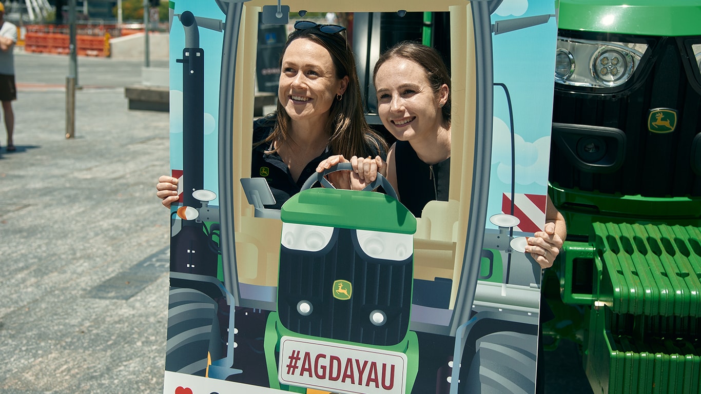 Two of women posing with a cardboard cutout of a truck.