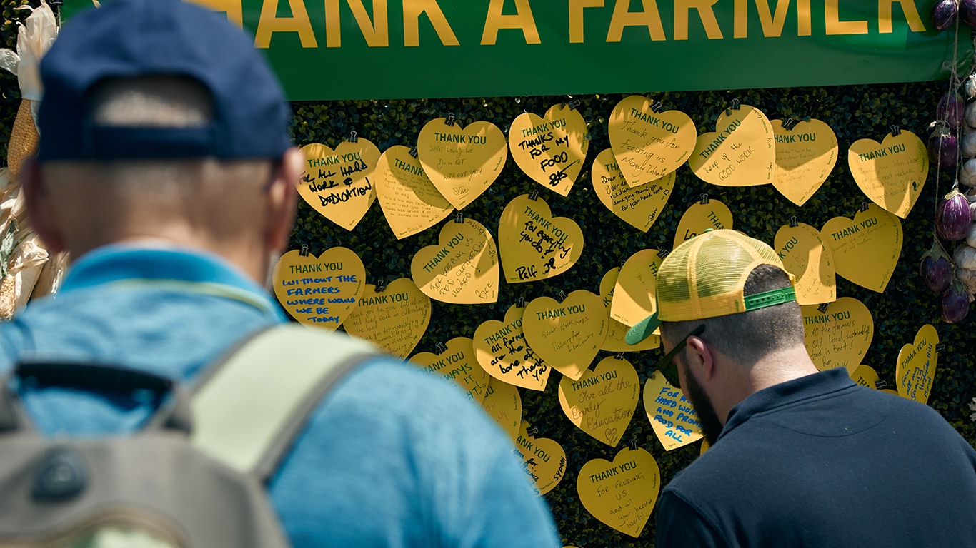 A group of people looking at yellow paper hearts with handwritten thank you messages for Aussie farmers.