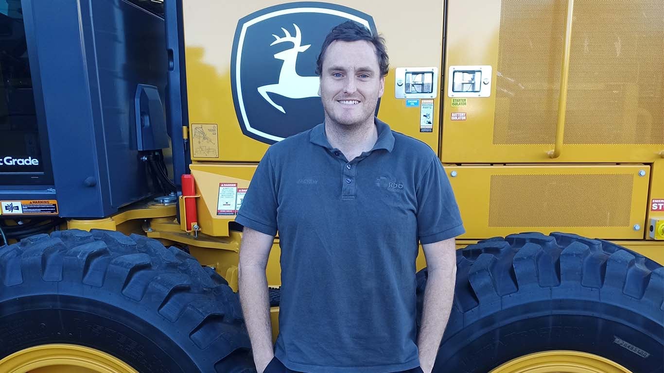 Andrew James standing in front of John Deere machinery.