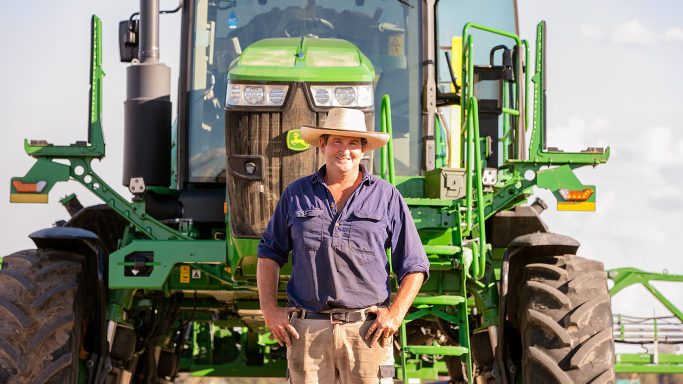 Farmer Angus Siddins standing in front of his 412R Sprayer in a paddock.