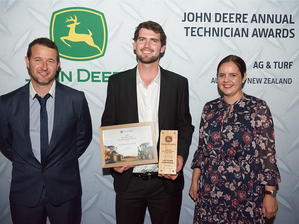 three people standing with one holding awards