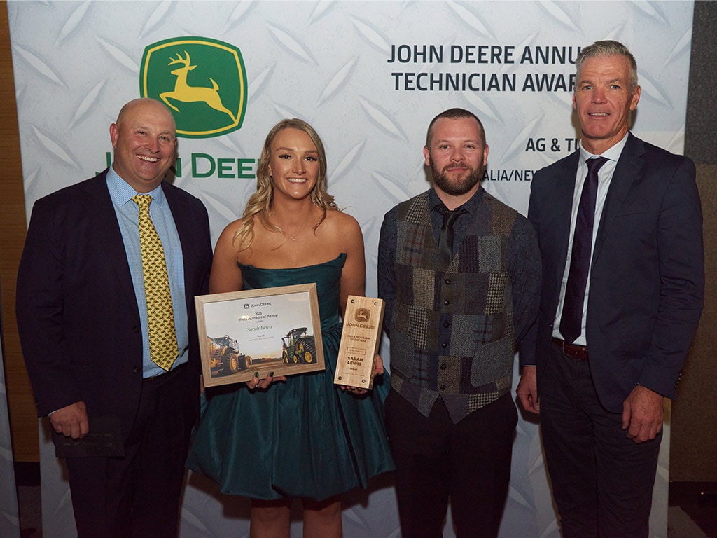 four people standing with one holding awards