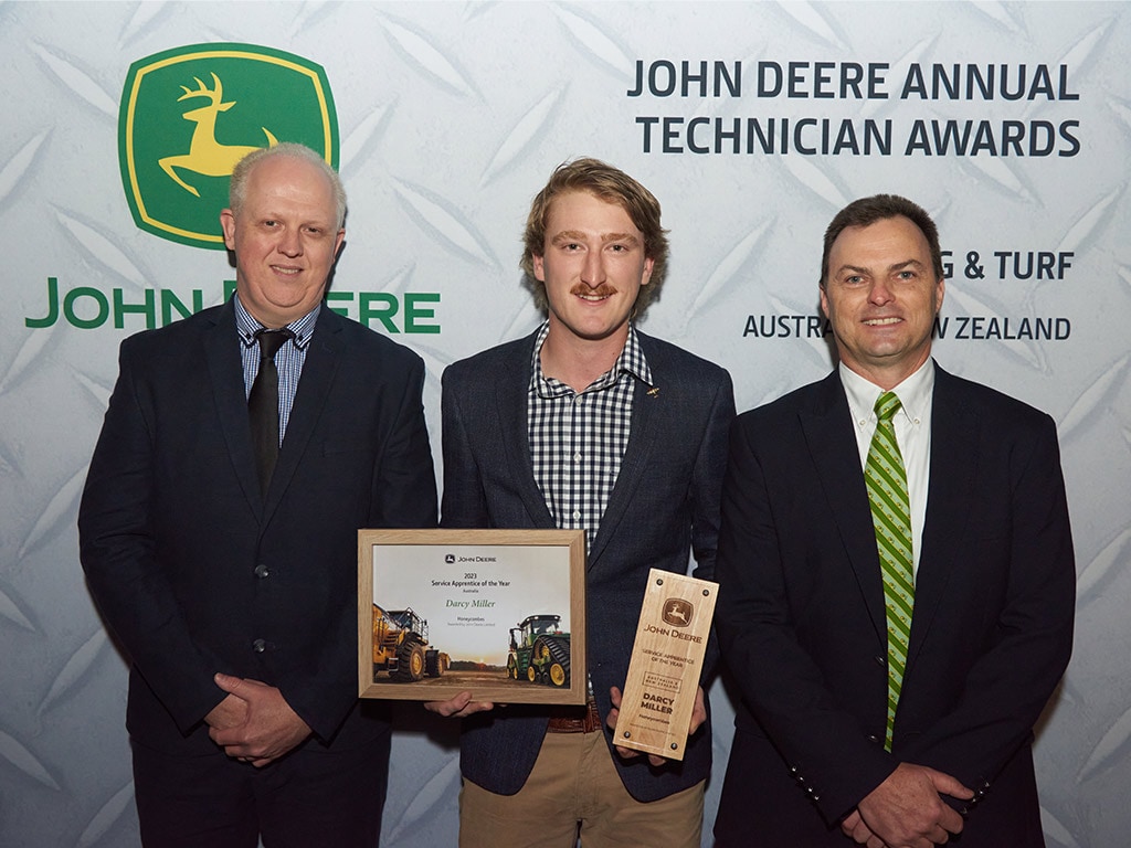 three people standing with one holding awards