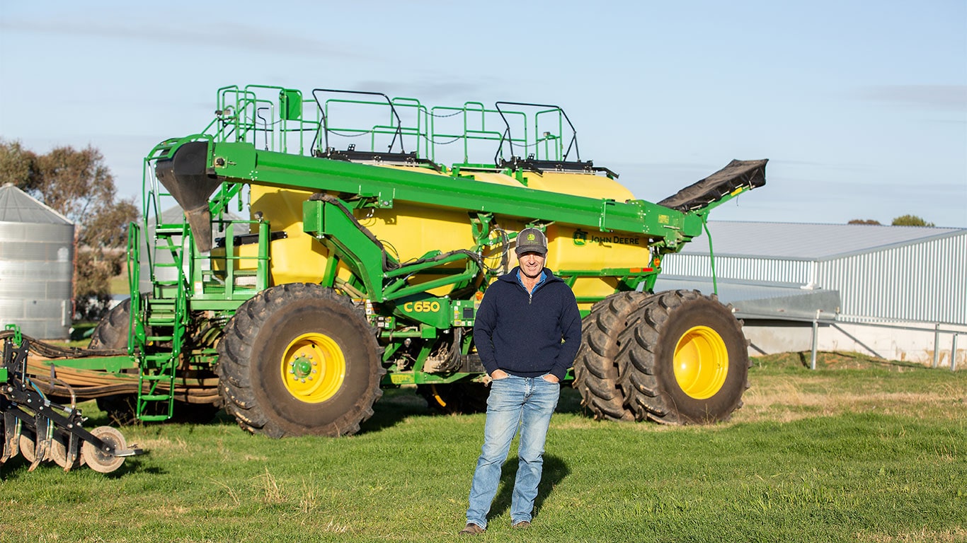 Man standing in front of John&nbsp;Deere C650 tow-behind Air Cart Seeder