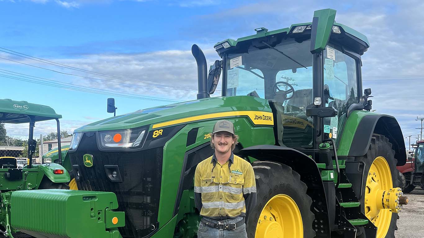Darcy Miller standing in front of John Deere machinery.