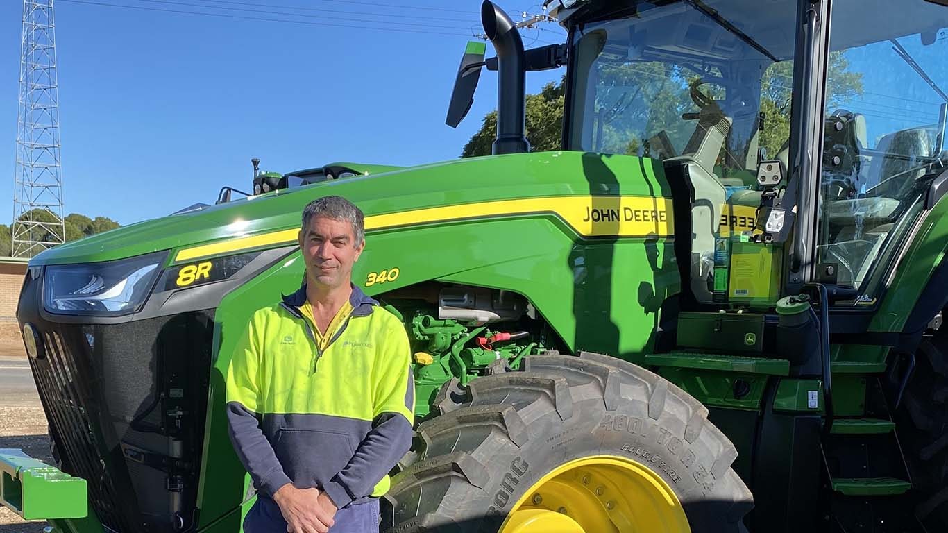 David Nicol standing in front of John Deere machinery outside.