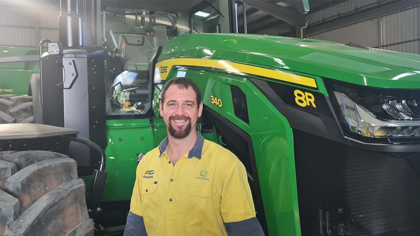 Francois Groenewald standing next to John Deere machinery.