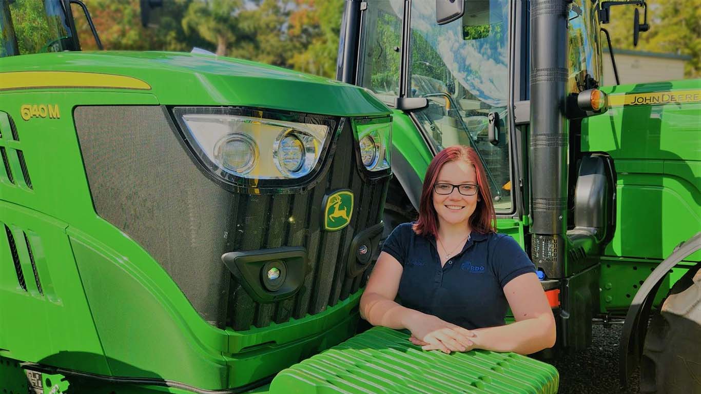 Kaylyn-Rose Netrval standing in front of John Deere machinery.