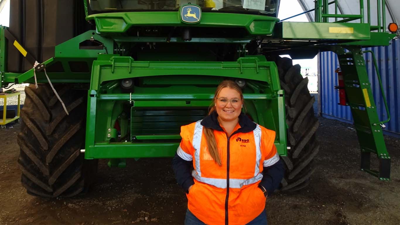 Kym Thorne standing in front of John Deere machinery.