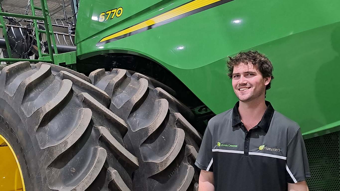 Lachlan Corridan standing next to John Deere machinery.