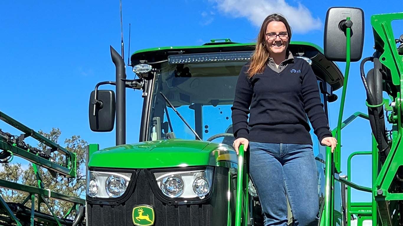 Lauren Cortes standing in front of John Deere machinery.