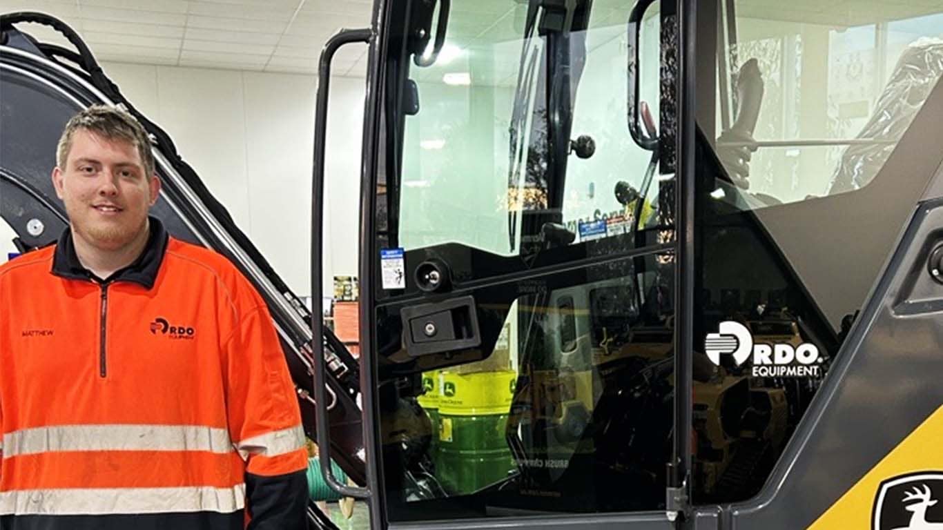 Matthew Giuntini standing in front of John Deere machinery.