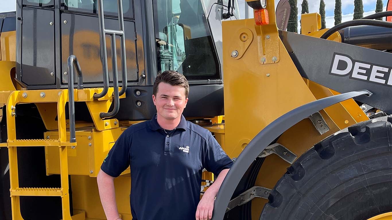 Mitchell Channer standing in front of John Deere machinery.