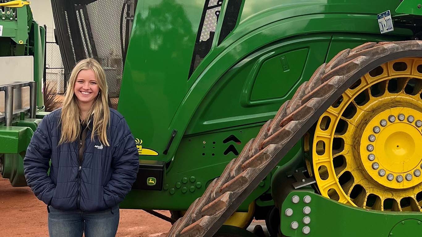 Poppy Blohm standing in front of John Deere machinery.