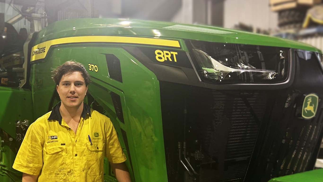 Salvatore Bettio standing in front of John Deere machinery.