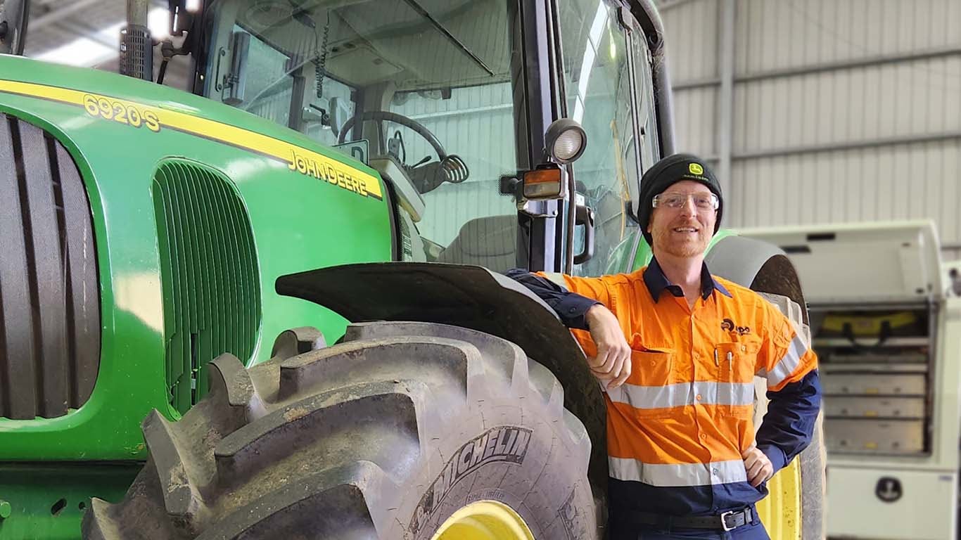 Vincent Powditch standing in front of John Deere machinery inside a factory.