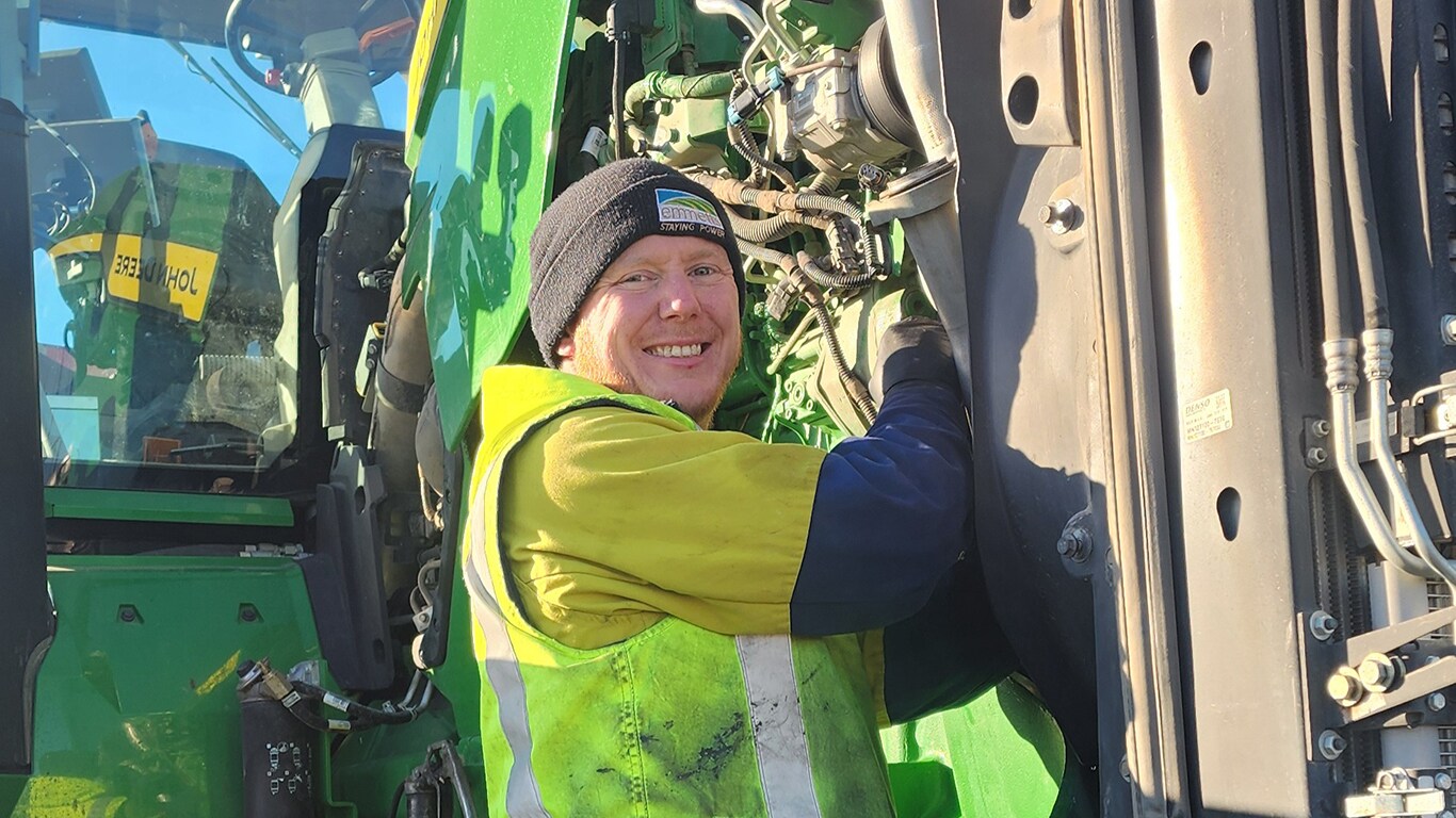 James Smart smiling in front of a tractor with its hood raised