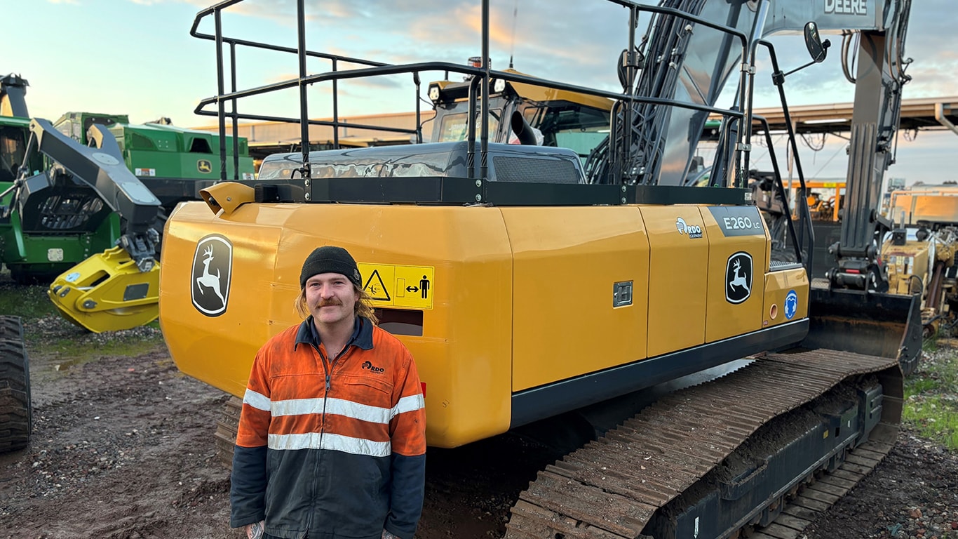 Andrew Moat smiling in front of a E260LC excavator