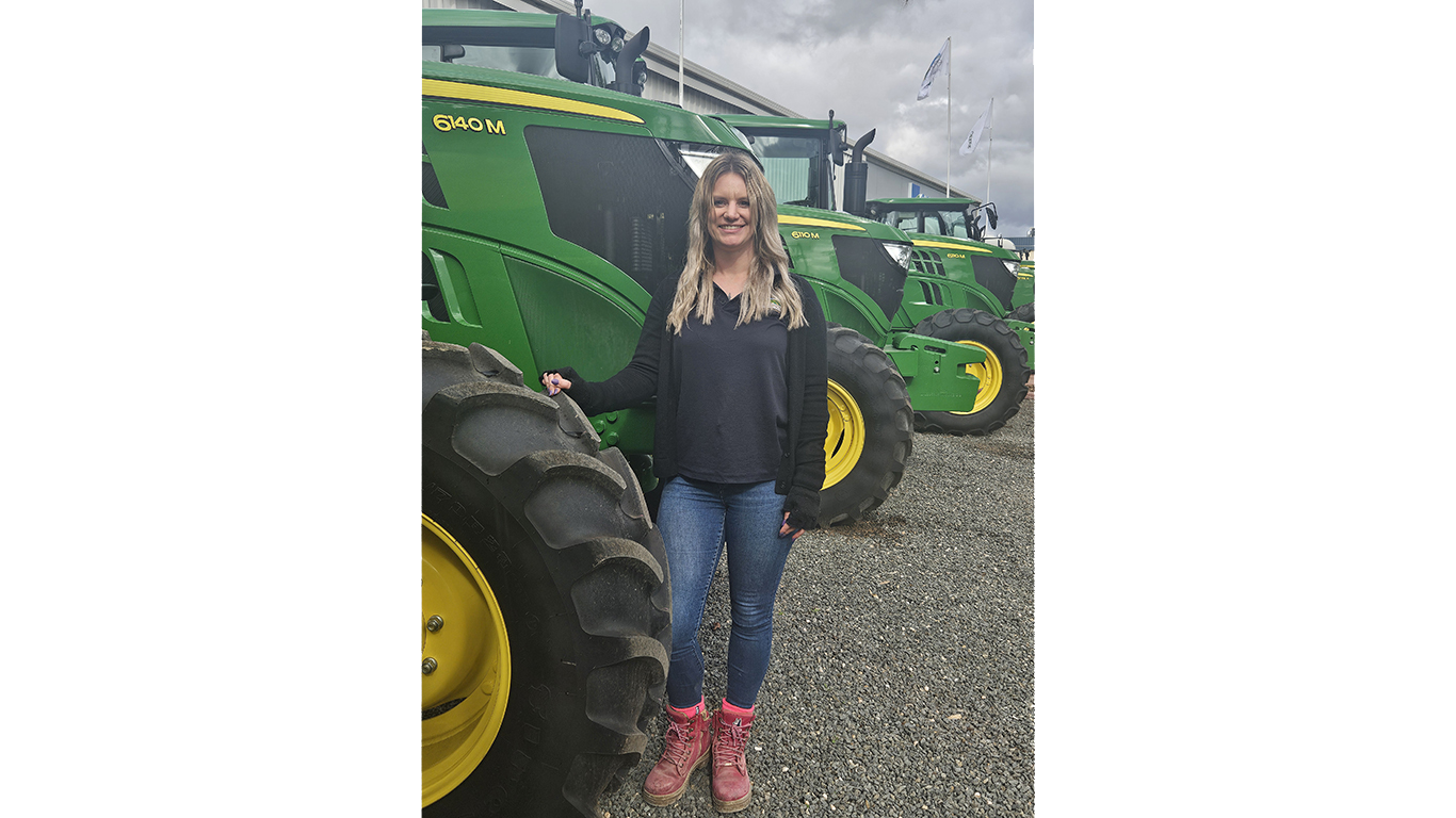 Belinda Gade smiling next to a 6140M tractor