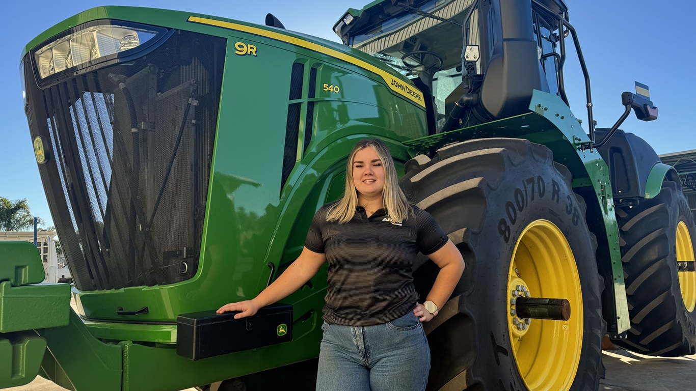 Hannah Goedhart-Hutchings smiling with one hand on a 9R 540 tractor