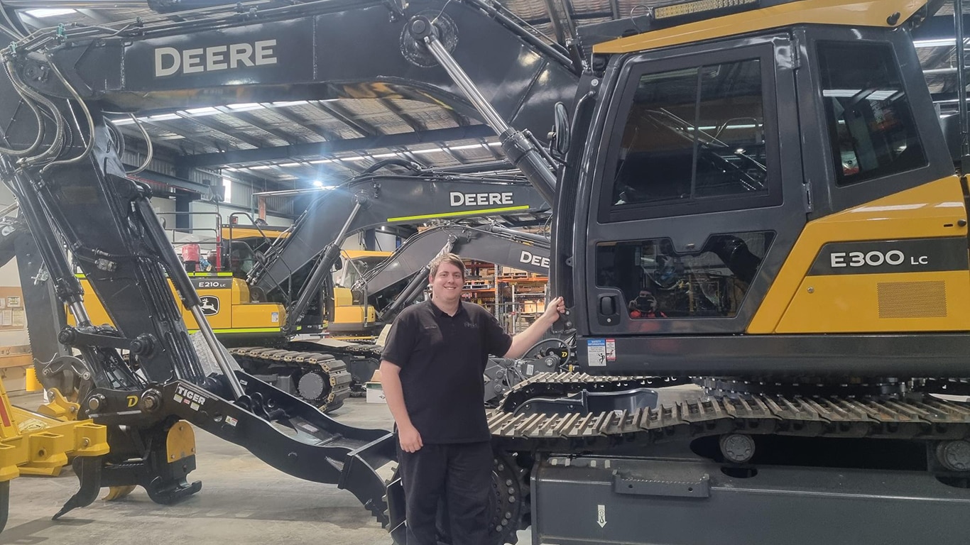 Matthew Giuntini smiling next to a E300 LC excavator