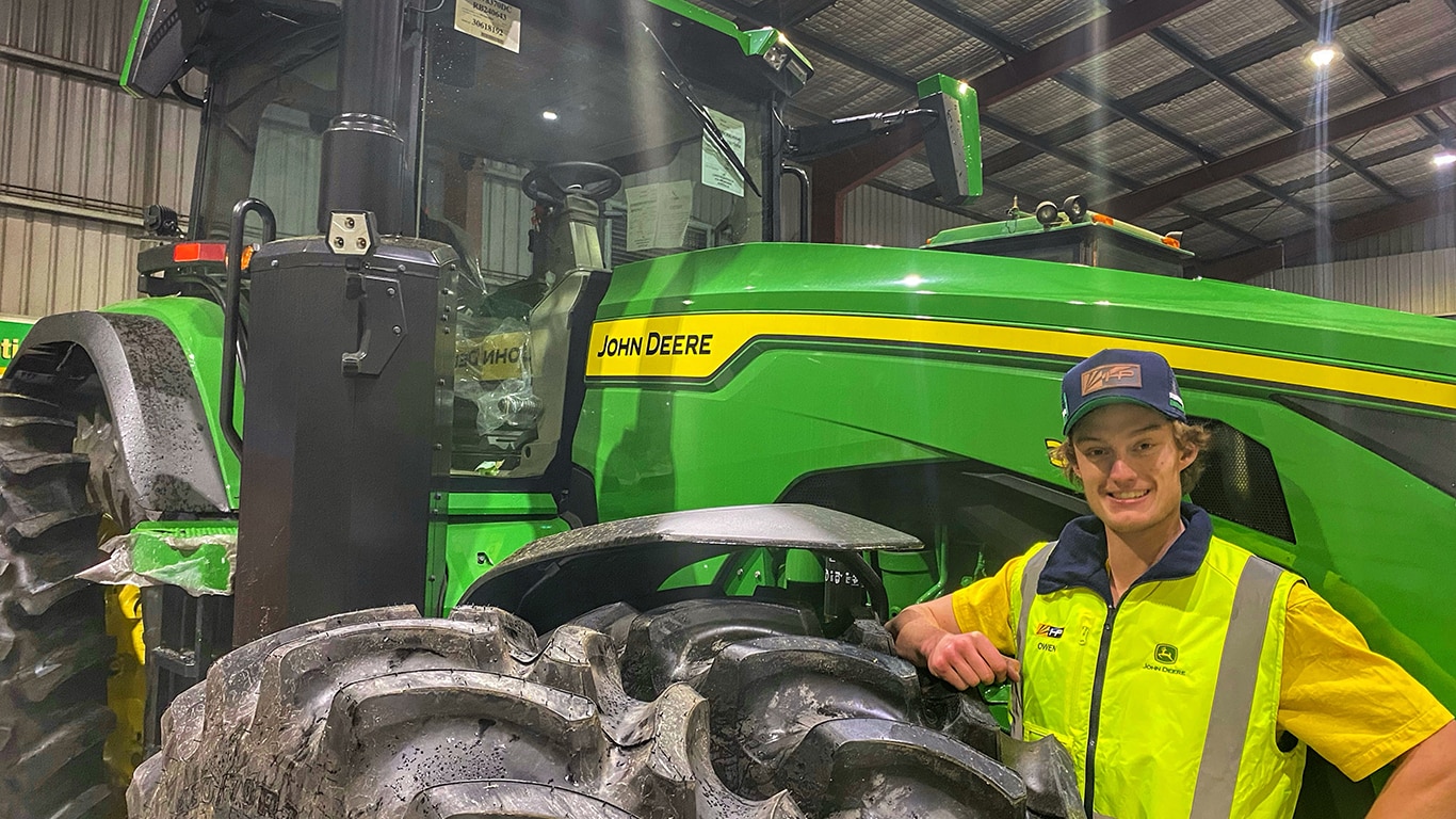 Owen Armstrong smiling with one arm on the wheel of a tractor