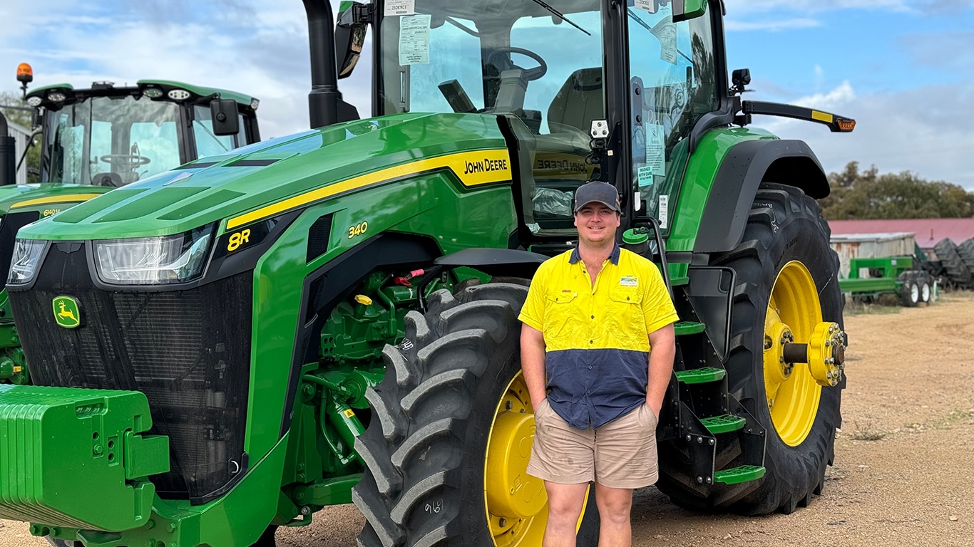 Sam Dyer smiling next to a 8R 340 tractor