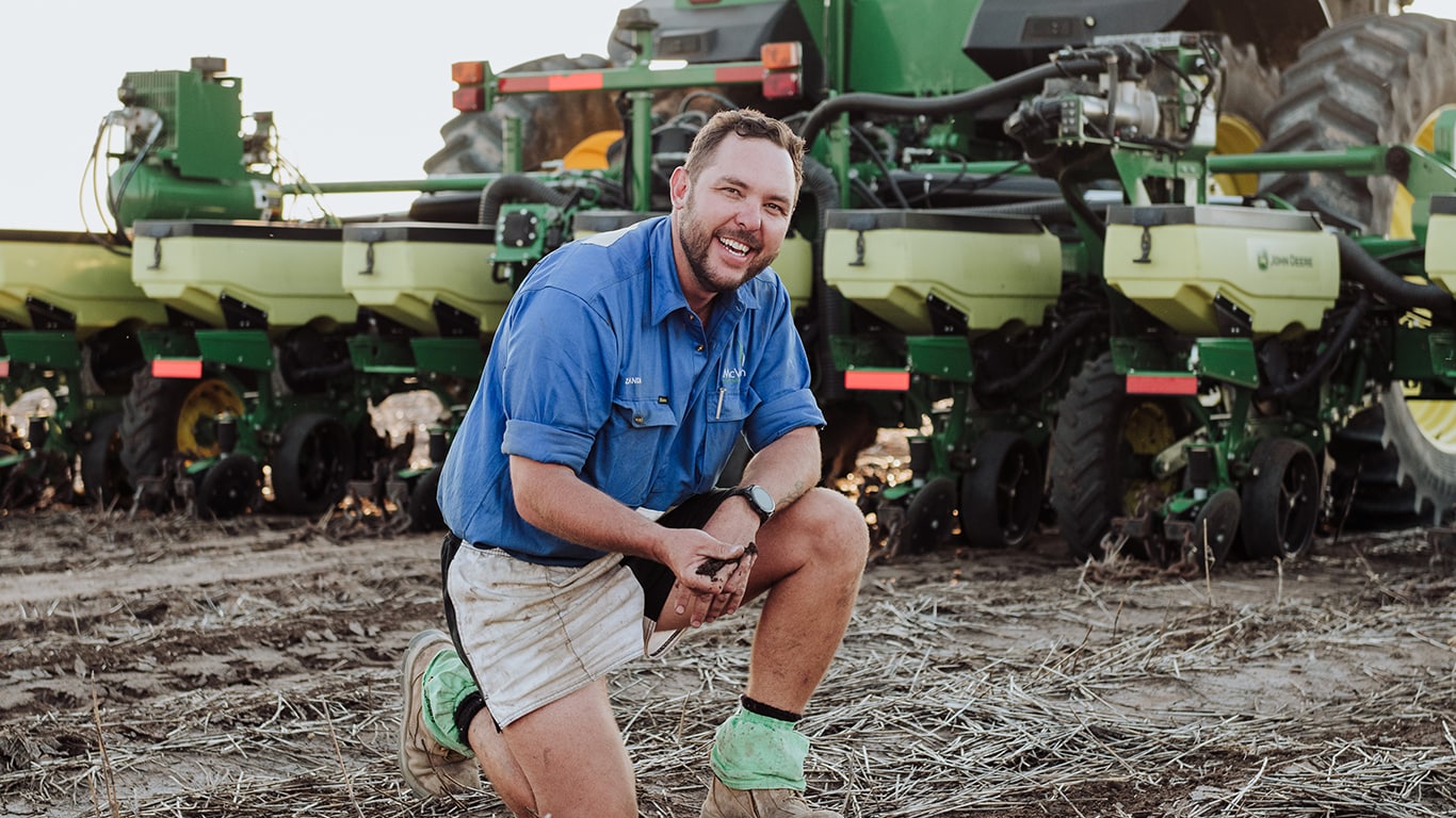  Farmer kneeling in front of John Deere planter