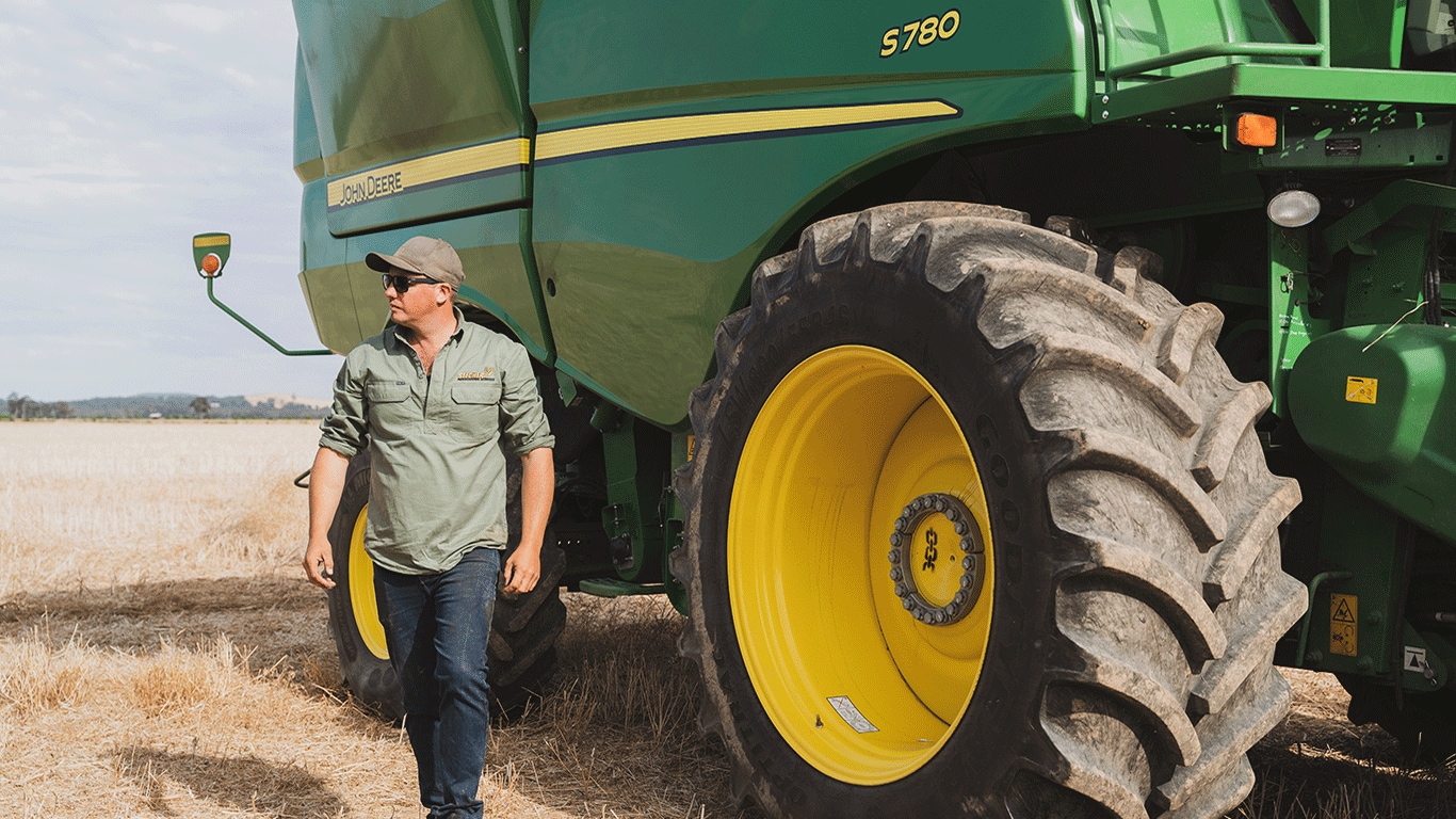 Out in the paddock on a bright day, Richard Stecher is dwarfed by his John Deere S780 combine harvester.