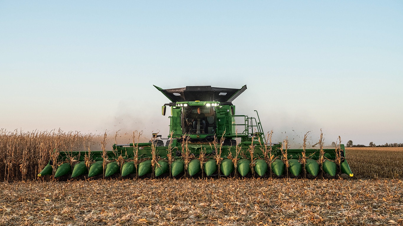 John Deere combine harvester with corn head in paddock