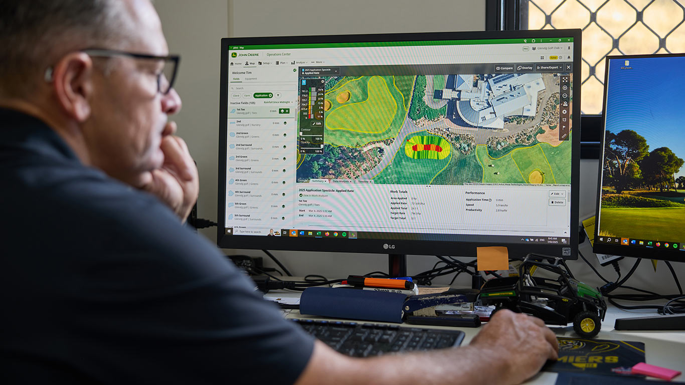 A man interacting with a computer using the John Deere Operations Center PRO Golf software.
