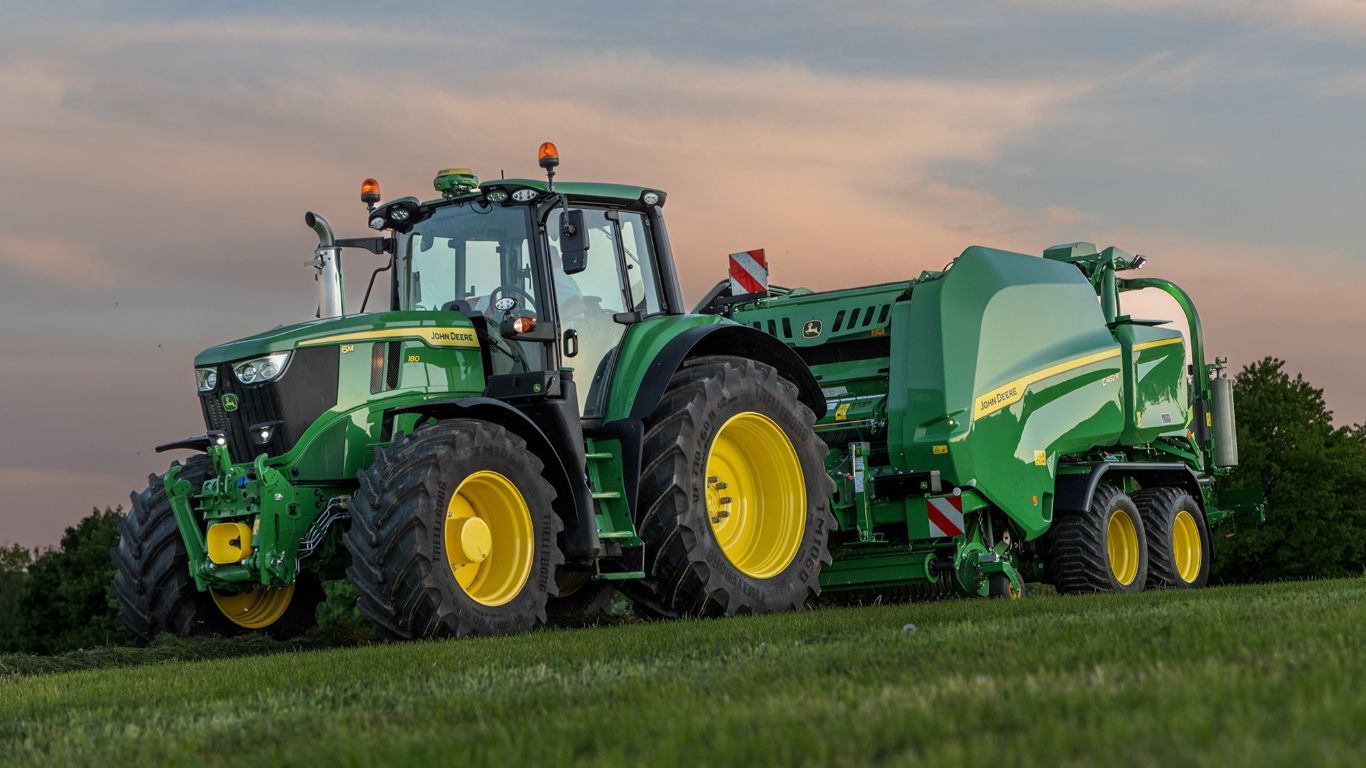 A John Deere tractor and baler in a field.