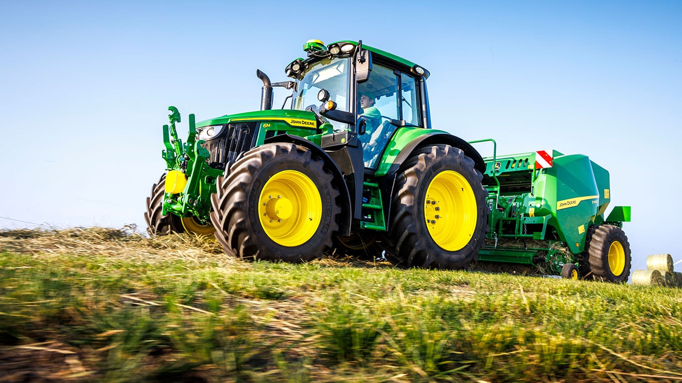 The new 6M 155 traveling through field towing a baler