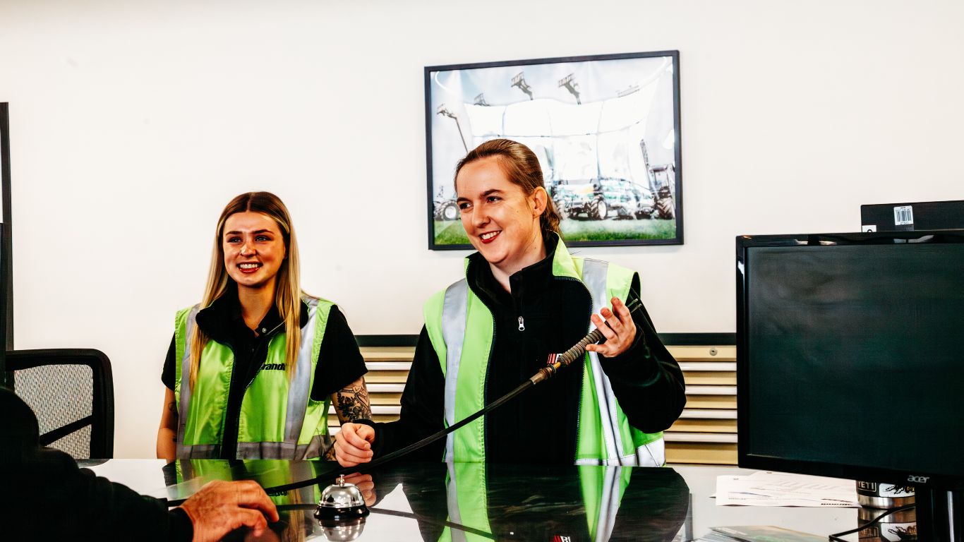 Two women in yellow vests standing in office with part.