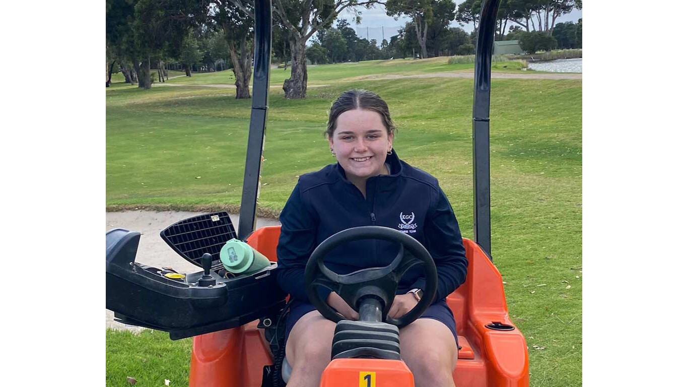 Olivia Cowan smiling at camera sitting on fairway mower
