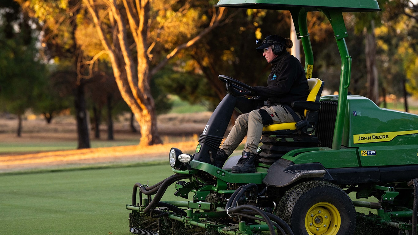Vicki Liddington using John Deere fairway mower in early morning light