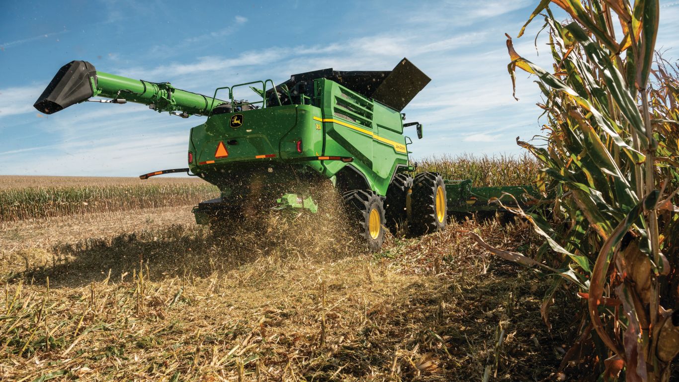 Back of large green combine harvesting crop